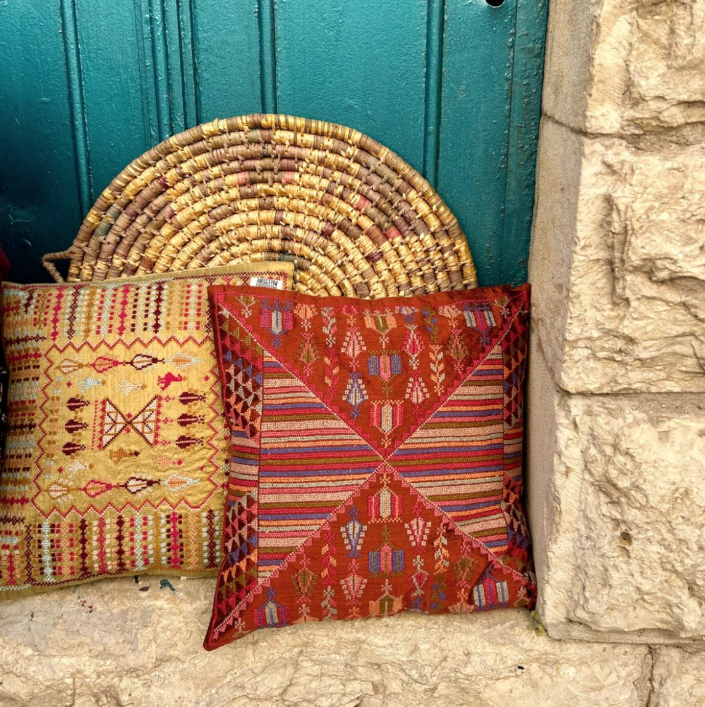Embroidered cushions against a blue wooden door