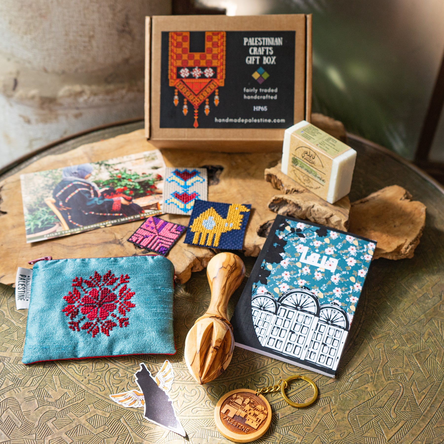 Collection of Palestinian crafts including a pouch, cards, and soap on a textured surface.