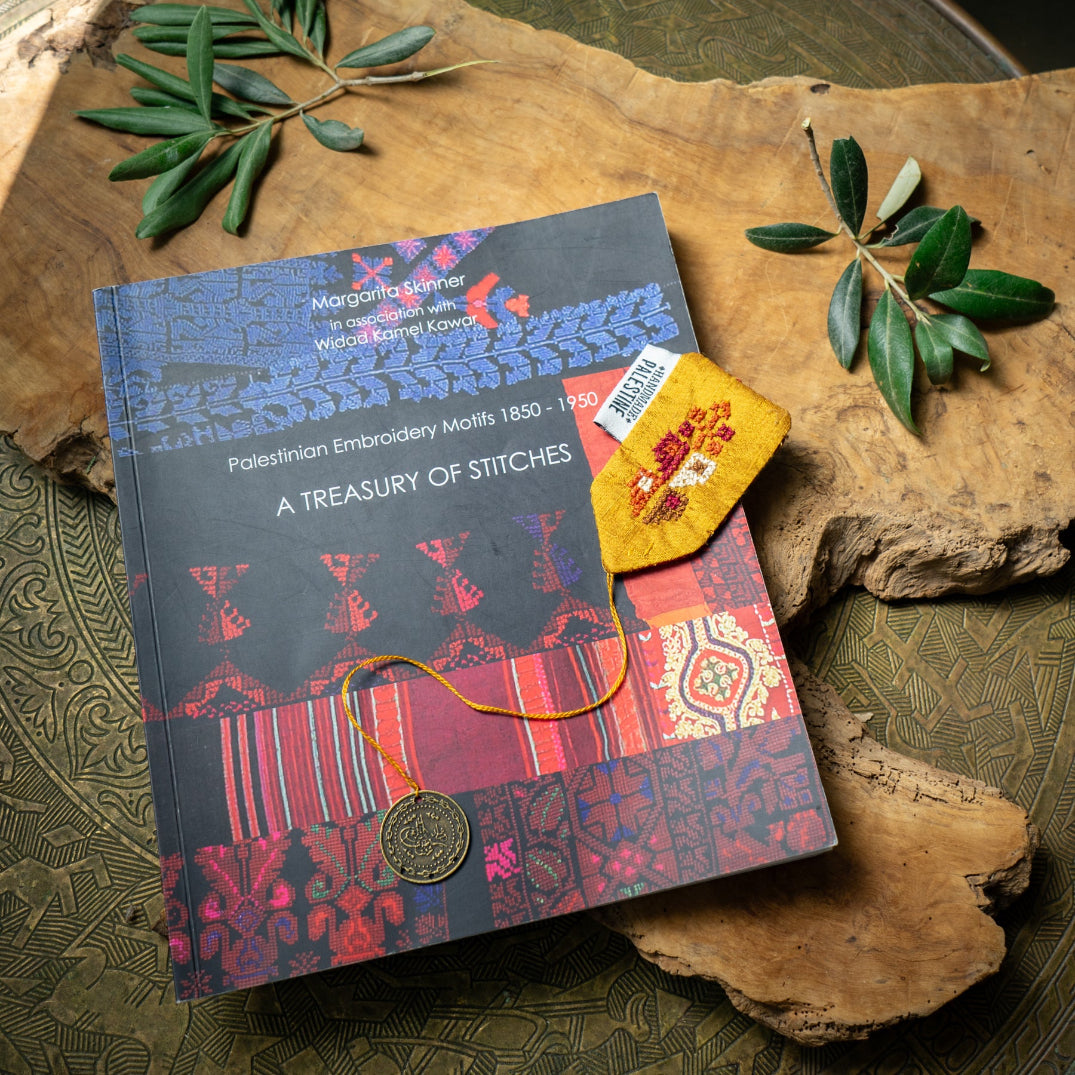 Book titled 'A Treasury of Stitches' with decorative elements on a wooden surface