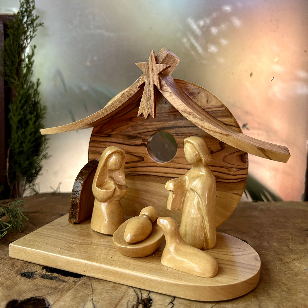Wooden nativity scene with stable and figures on a wooden base.