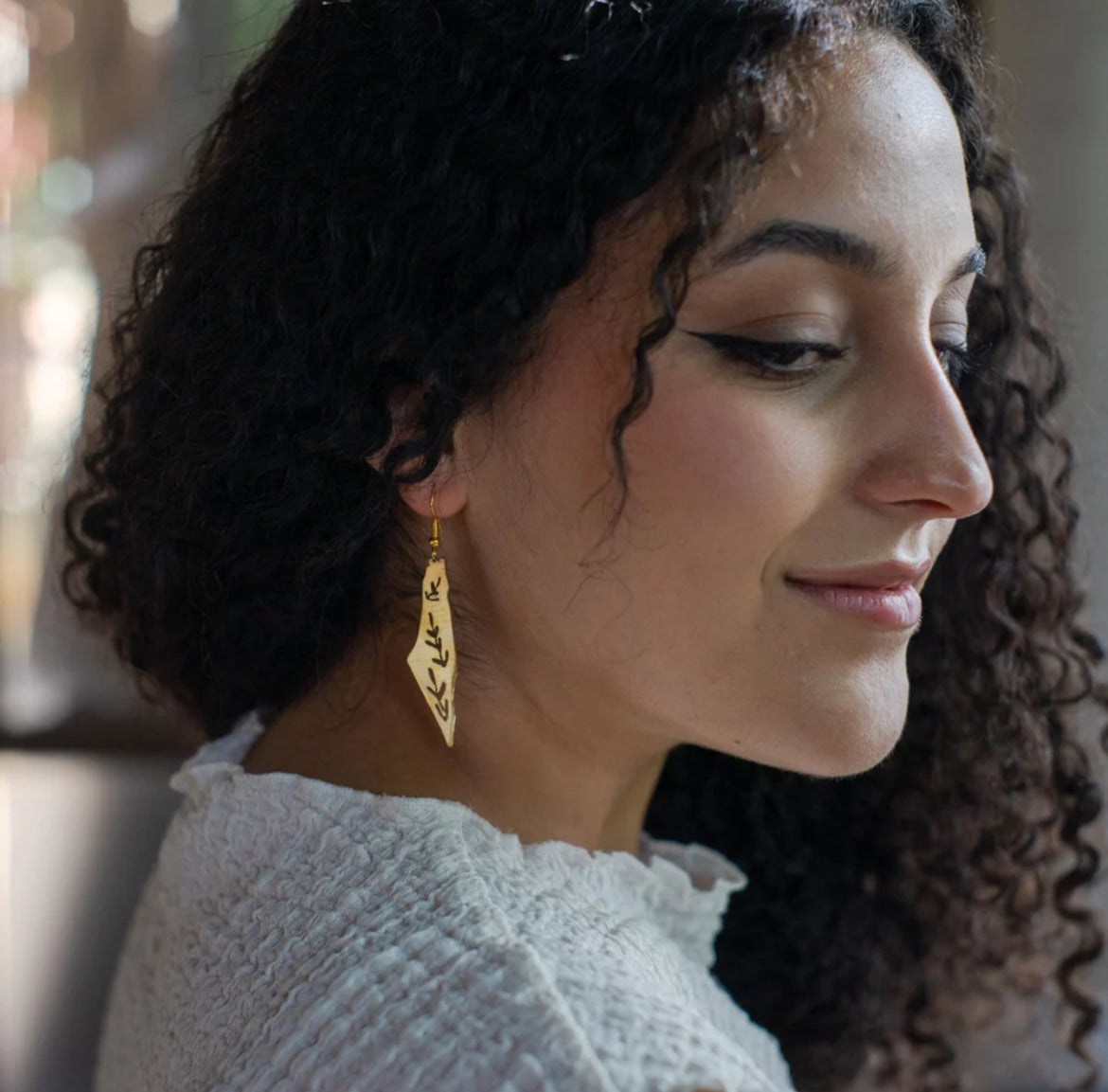 Palestinian woman wearing olive leave map of Palestine brass earrings