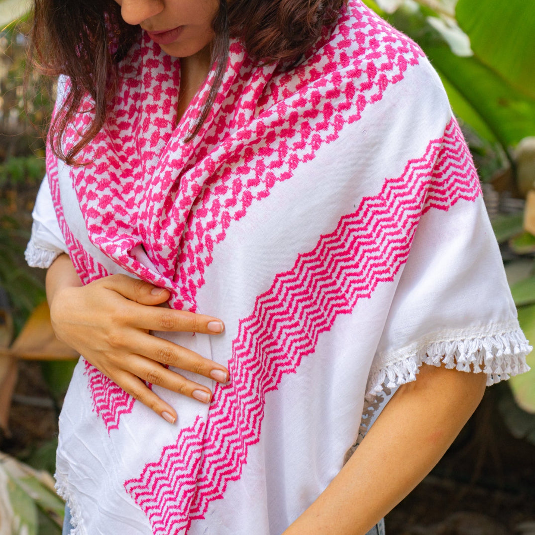 Palestinian woman wearing a white and pink patterned scarf called keffiyeh with a blurred natural background