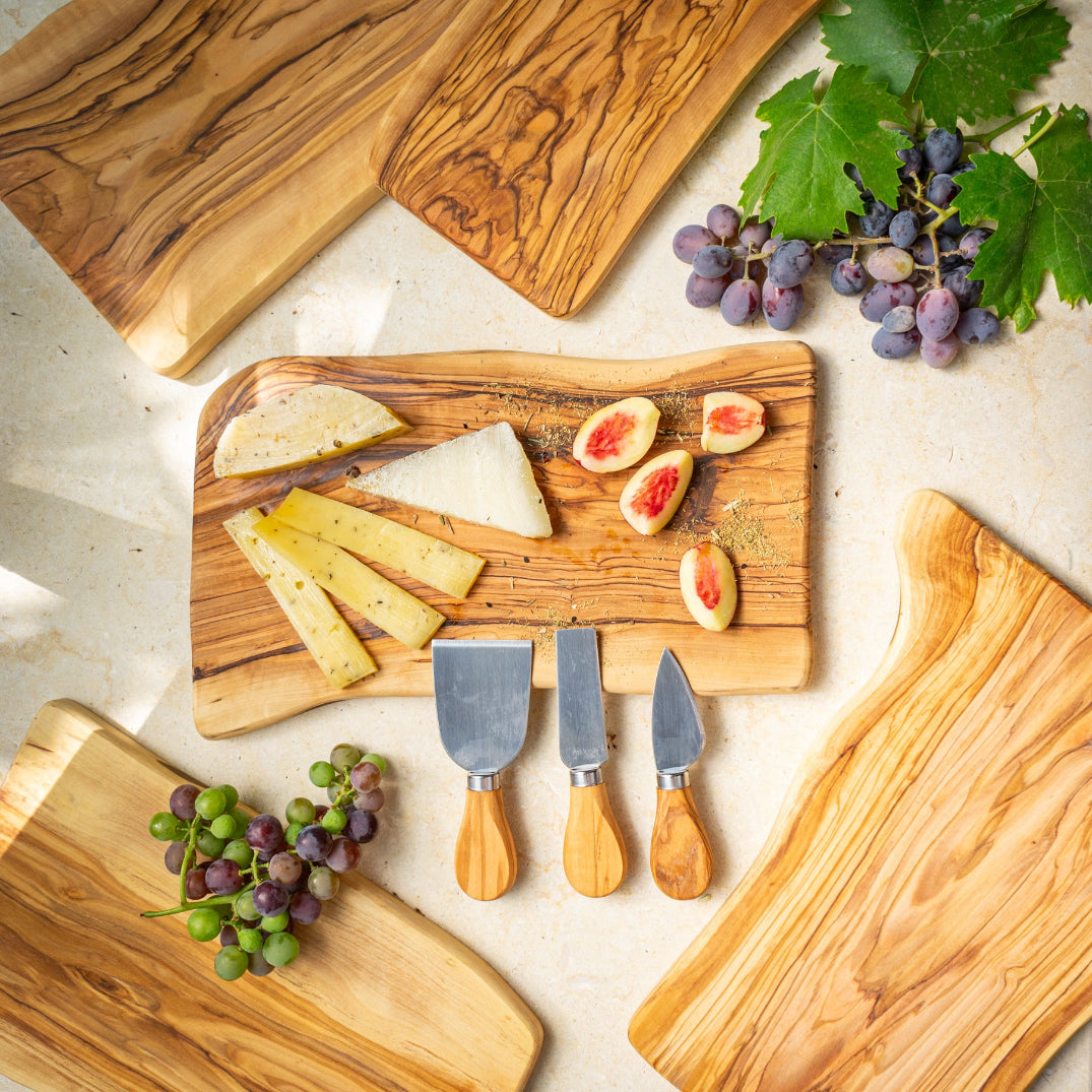 Wooden cutting boards with cheese, figs, and grapes on a light surface.