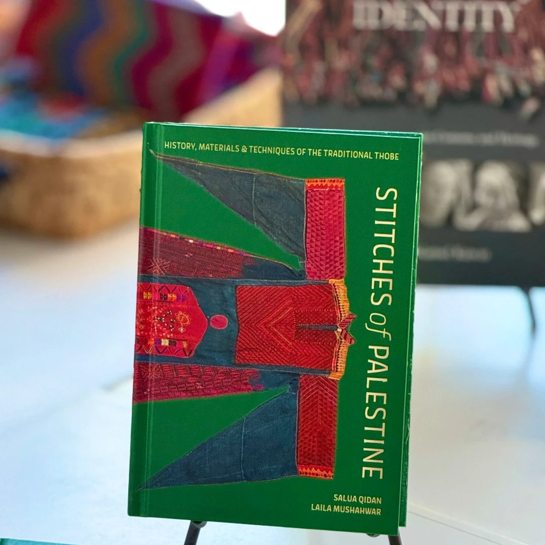 Book titled 'Stitches of Palestine' on a stand with blurred background