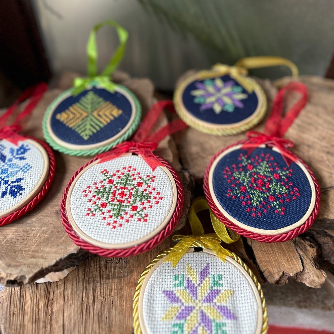 A collection of hand-embroidered Christmas tree ornaments with Palestinian tatreez in various colors.