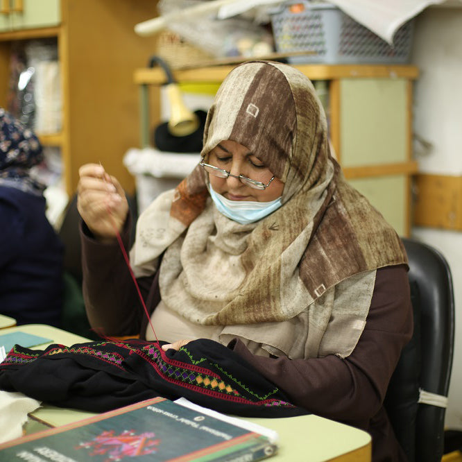 women artisan from gaza embroidering a shawlat atfaluna centre